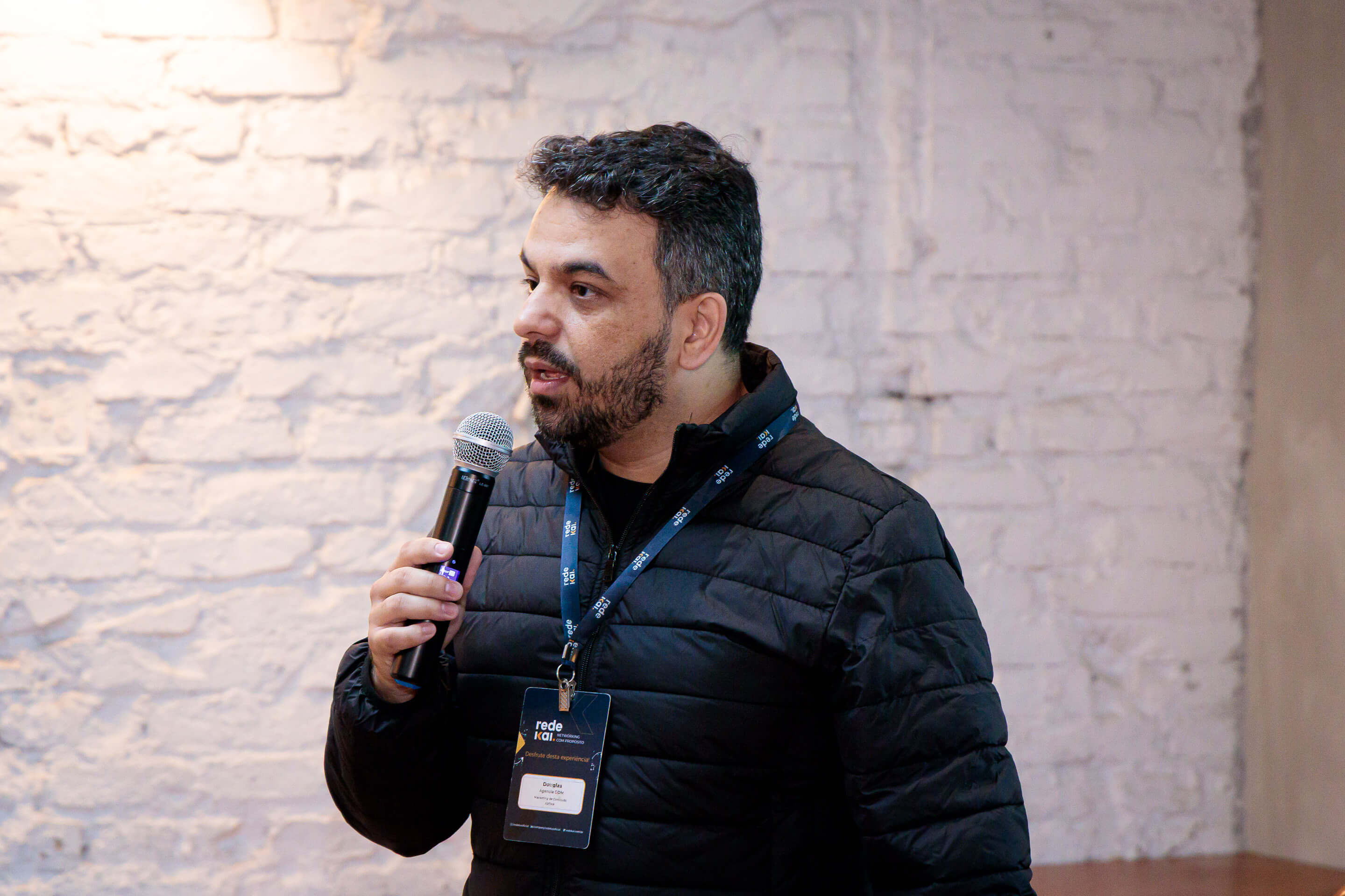 Douglas Oliveira palestrando com microfone em evento